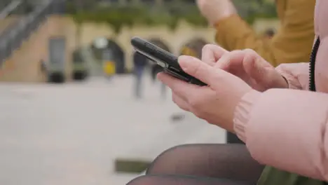 Close Up of Two Women Sitting Outside Using Phones