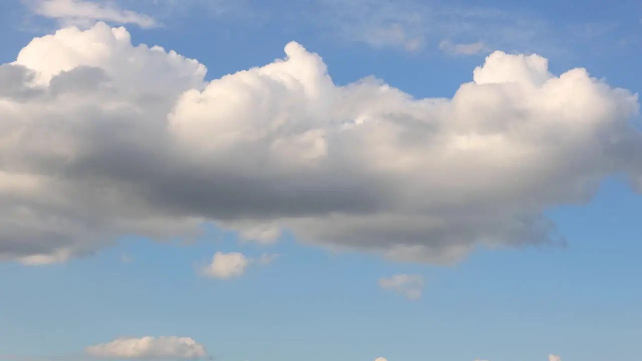 Cloud formation texture and detail of cumulus clouds growing and passing by against a clear soft blue sky