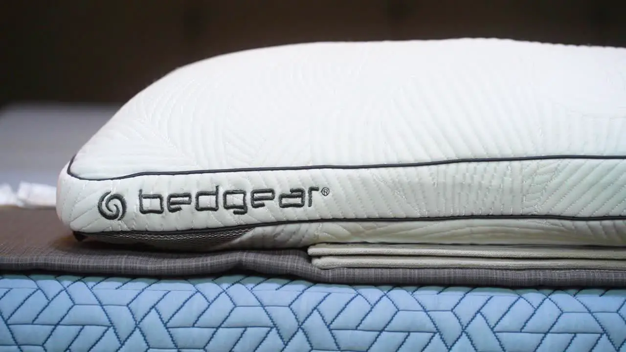 A Brand New White Bedgear Logo Performance Technology Cooling Stain Resistant Pillow Sleeping Cushion on a bed inside a mattress store