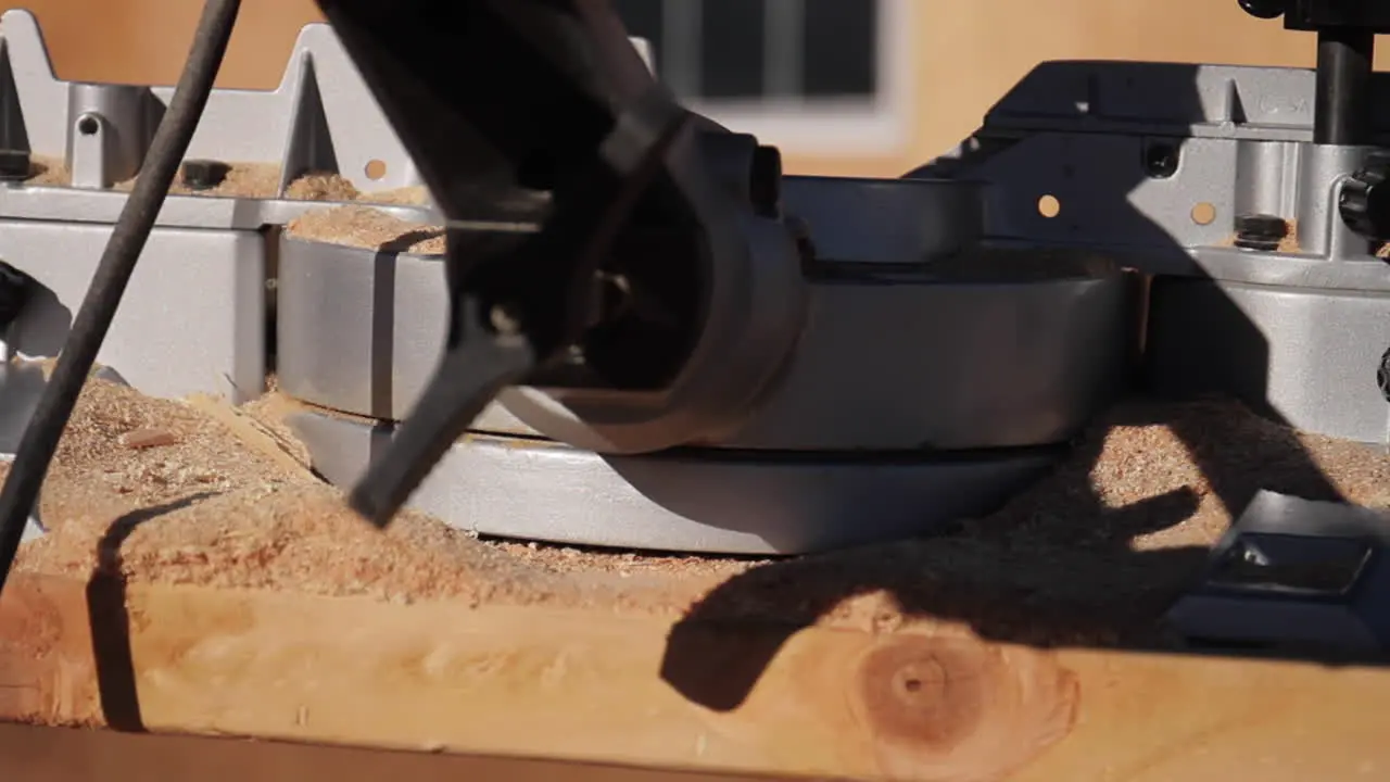 Slider Shot of Miter Saw on Wood with Glasses and Sawdust