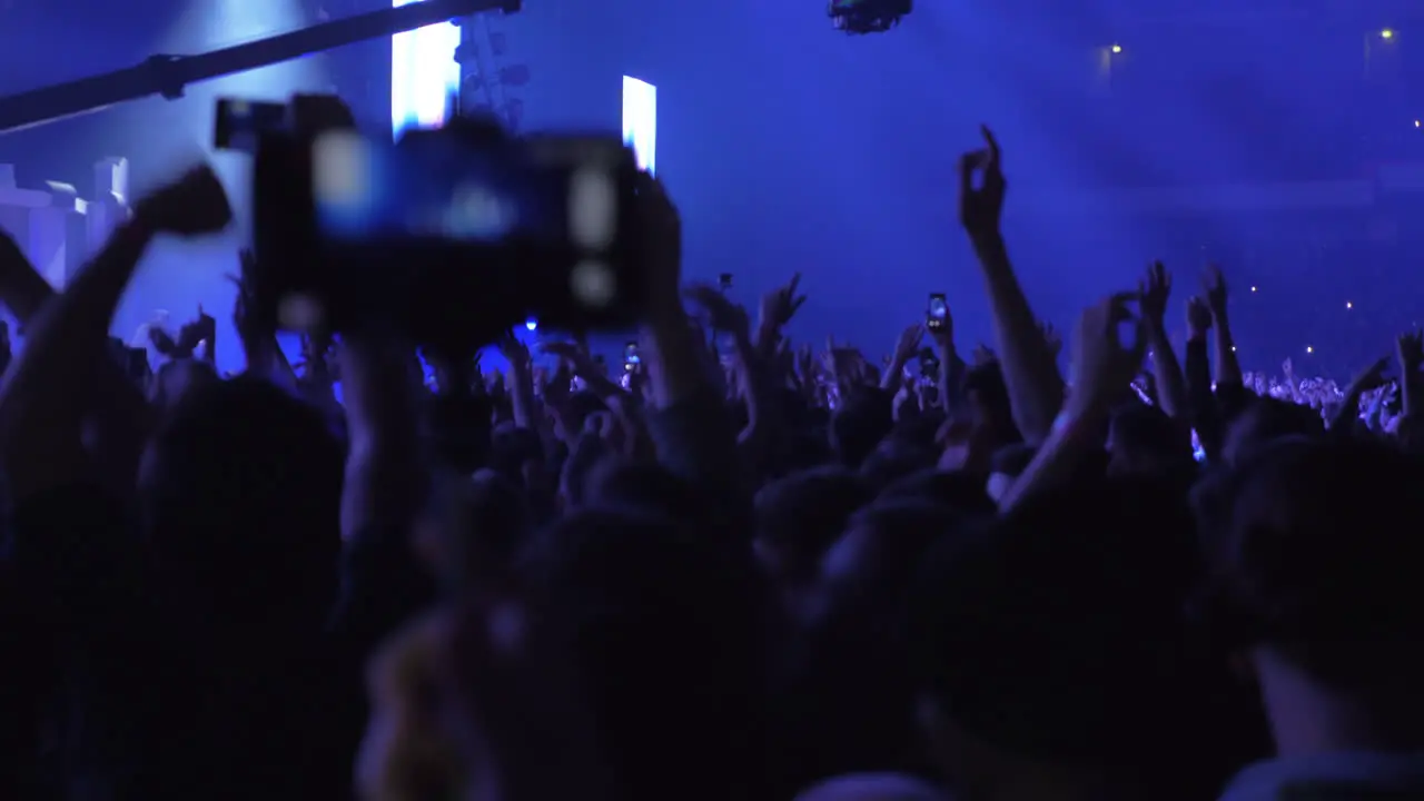 People dancing and raising hands up at the concert