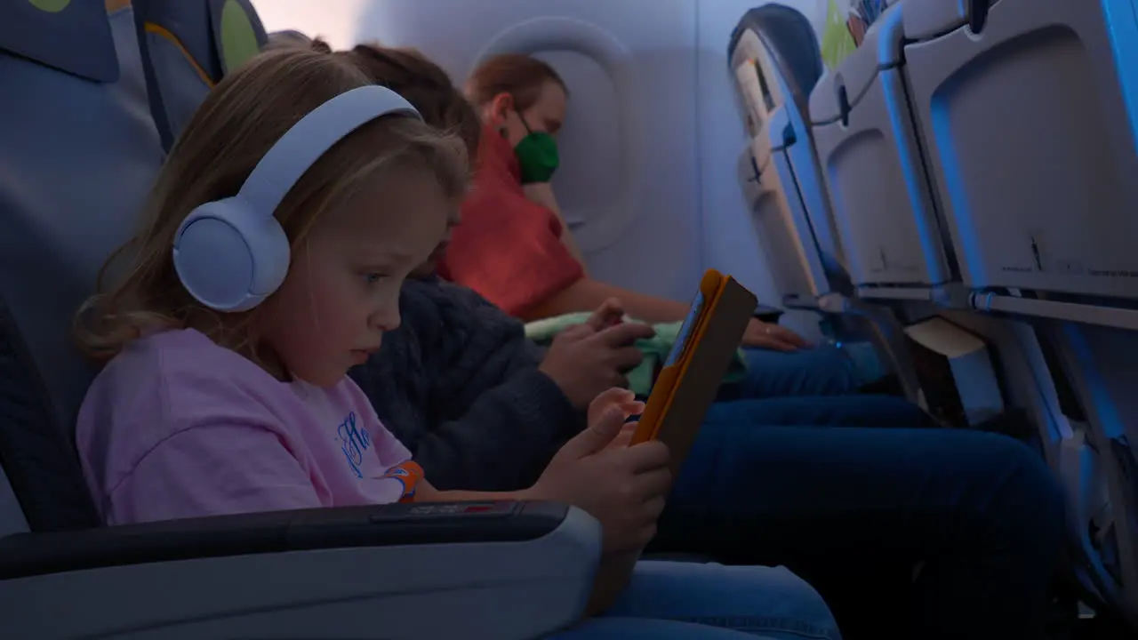 Sleeping mother and kids with gadgets traveling by plane