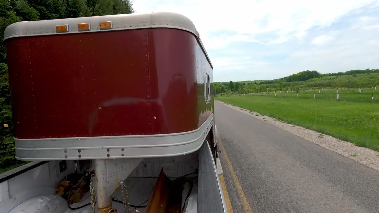 Pickup truck pulls horse trailer in countryside road fast back POV view