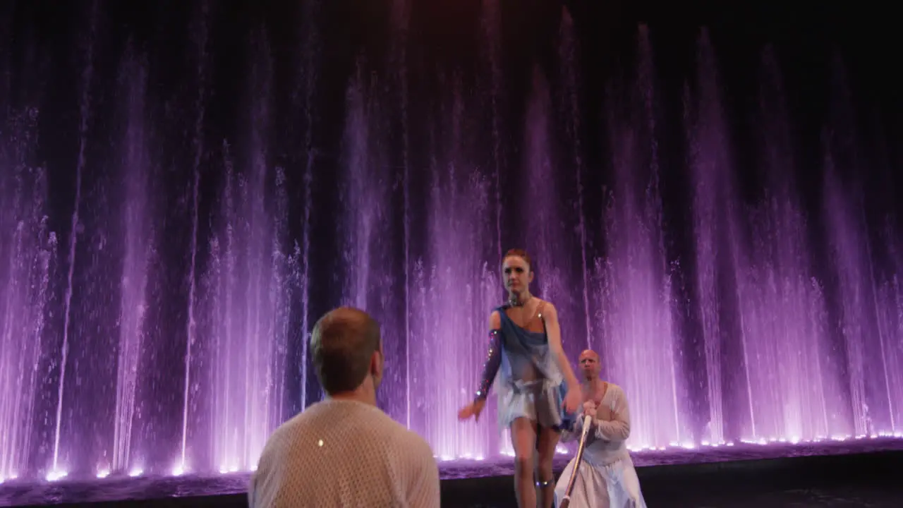 Group of acrobats making act with pole against colorful fountains Moscow Russia