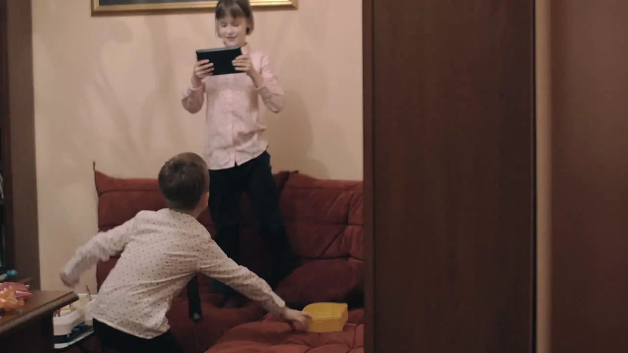 Boy fooling and dancing when girl taking video with tablet PC