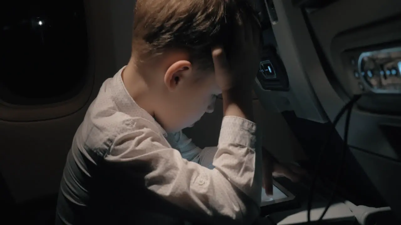 Boy traveling by plane and playing chess game on digital tablet