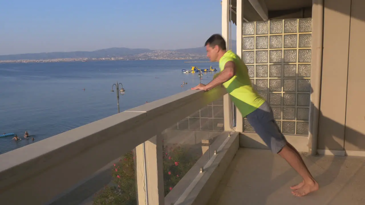 Man beginning push ups on the balcony with sea view background