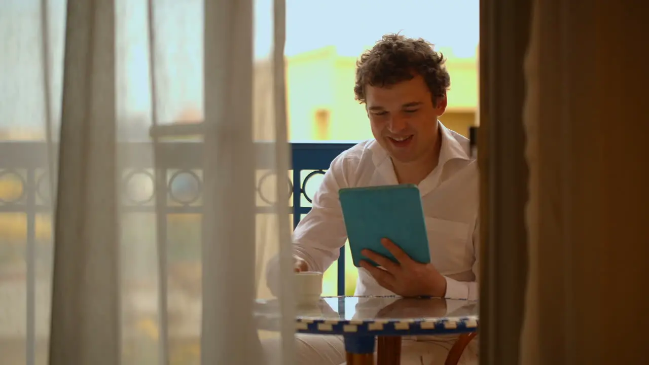 Man with laptop having tea on the balcony