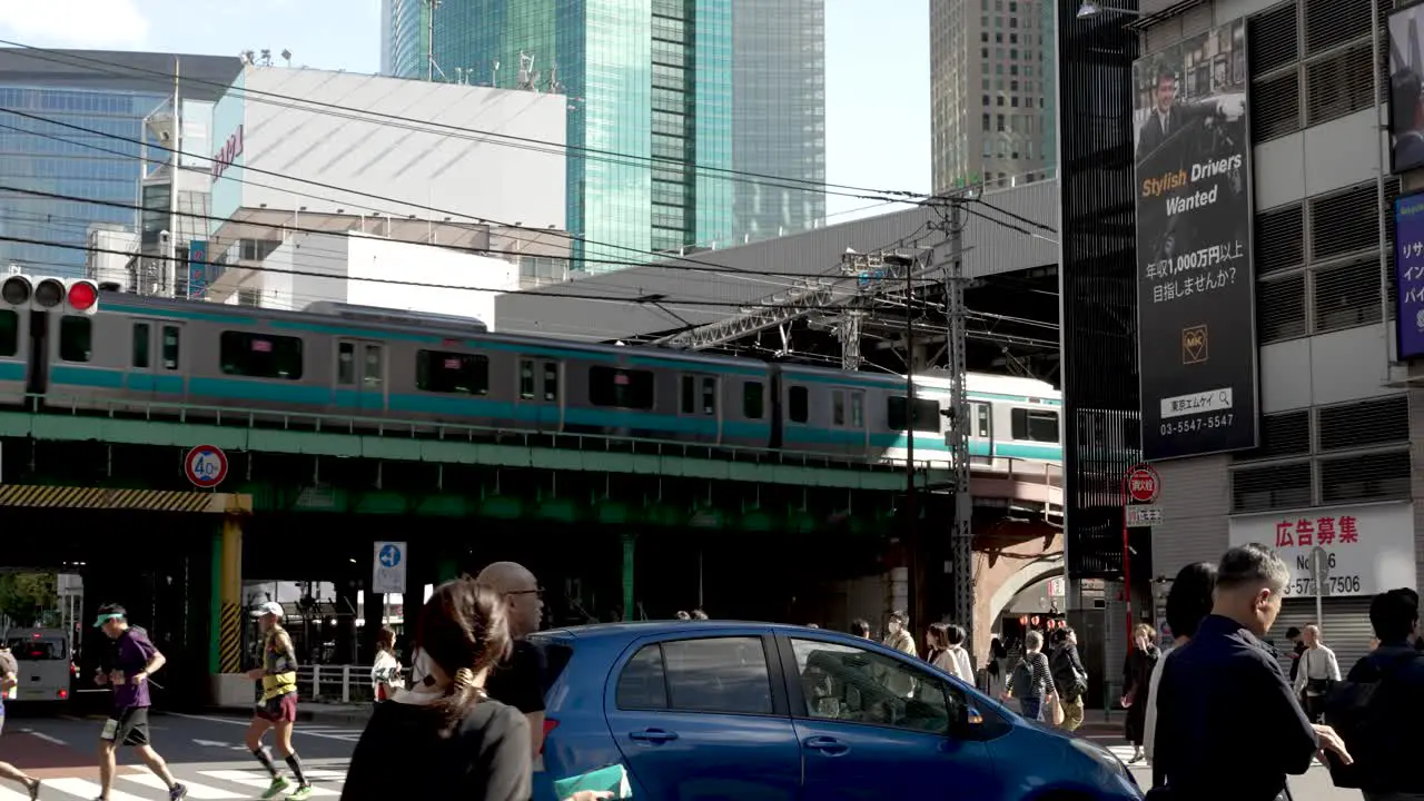 Daytime capture of the elevated train track of the Tokyo Metro Tozai Line at Shimbashi Station in Japan is depicted with vibrant city pedestrian zones and visible car traffic