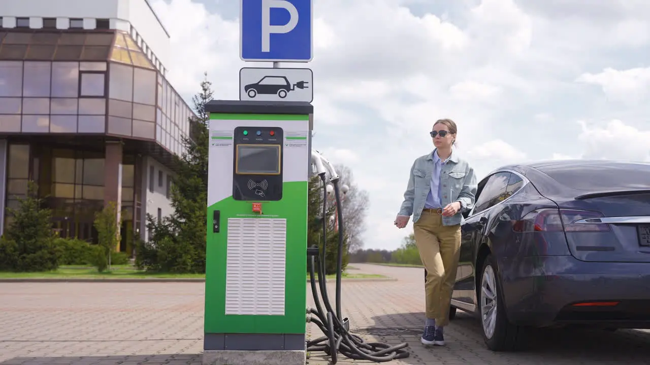 Young woman getting of an electric car