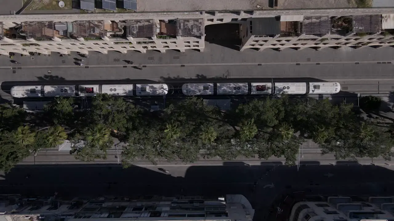 Tram driving on rails through city streets overhead aerial view