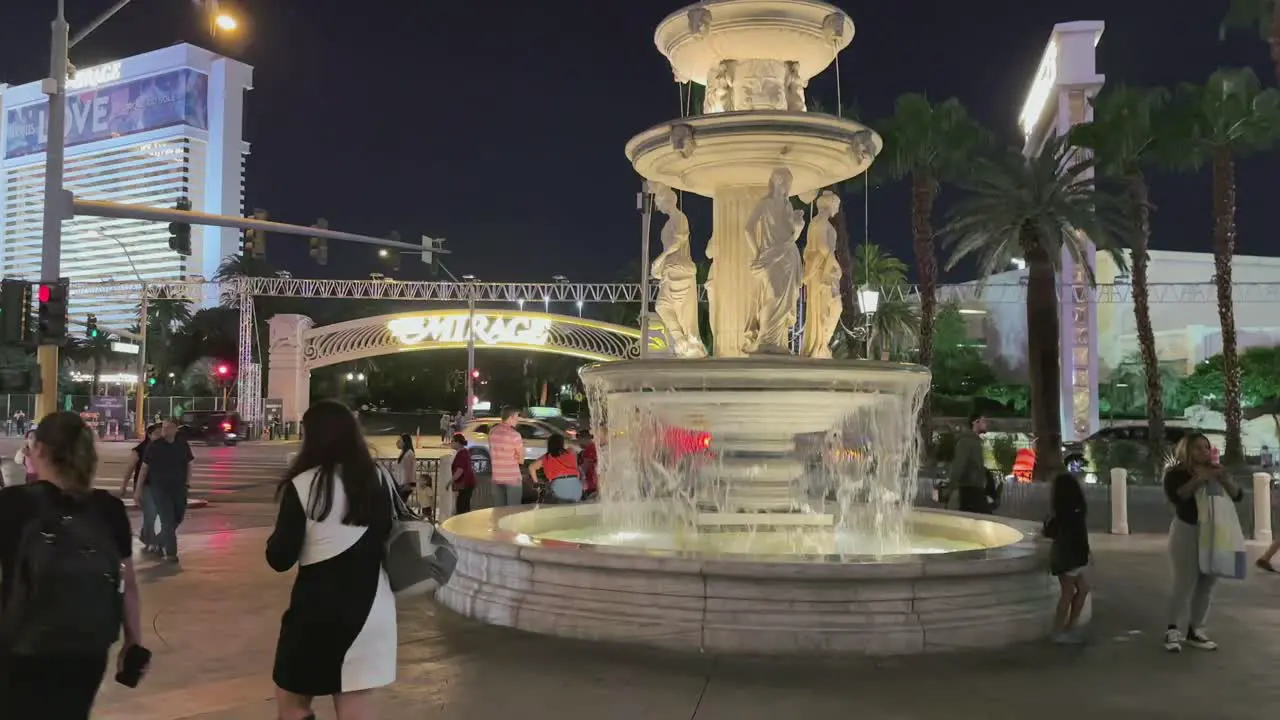 People at night on the Strip in Las Vegas with lit fountain and cascading water