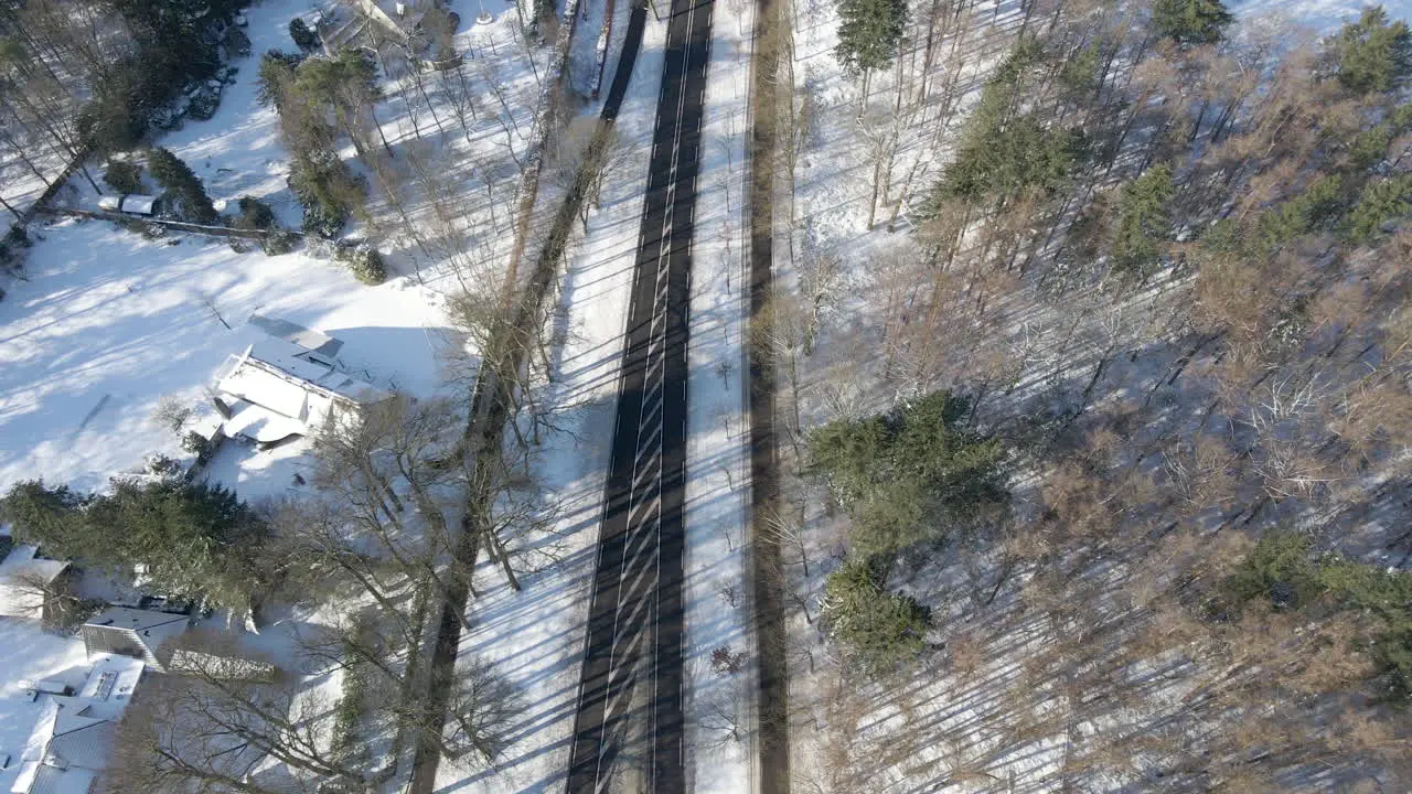 Top down aerial of empty road running through forest in winter