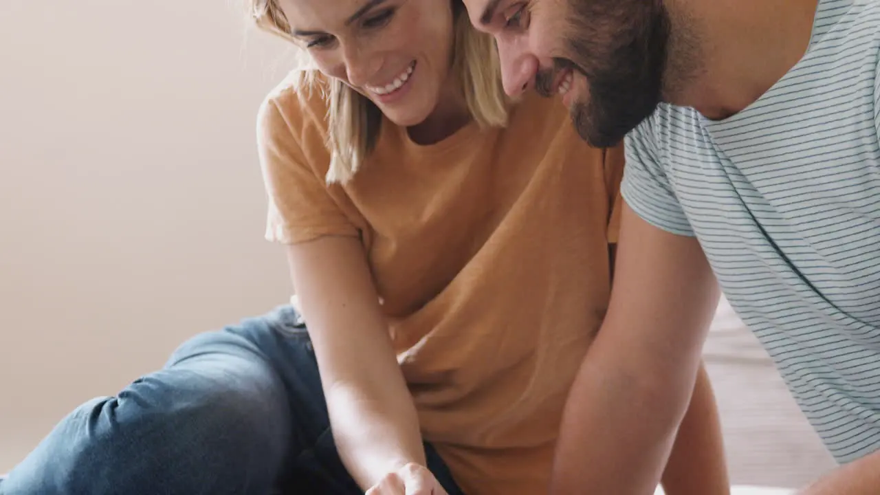 Loving Parents With Newborn Baby Lying On Bed At Home In Loft Apartment