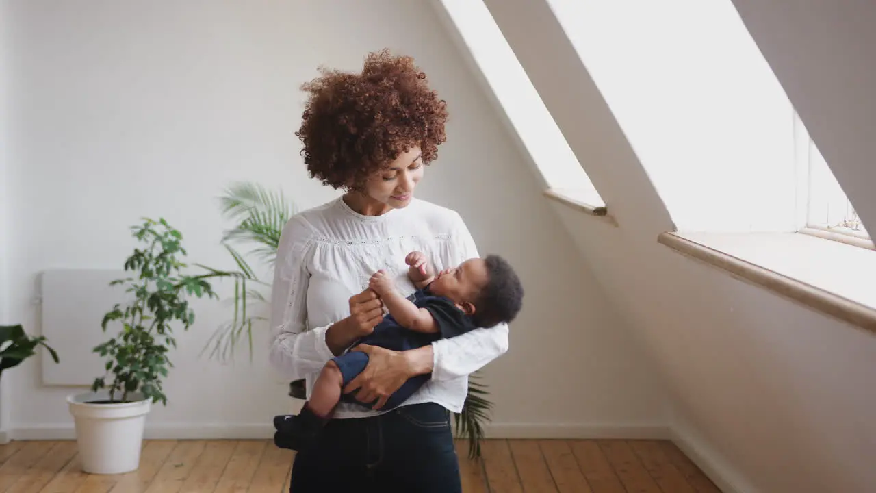 Loving Mother Holding Newborn Baby Son At Home In Loft Apartment