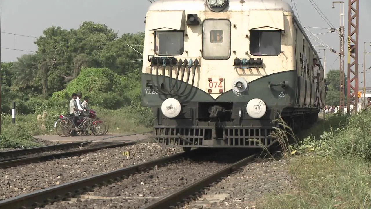 People wait to cross railroad tracks as a train comes through