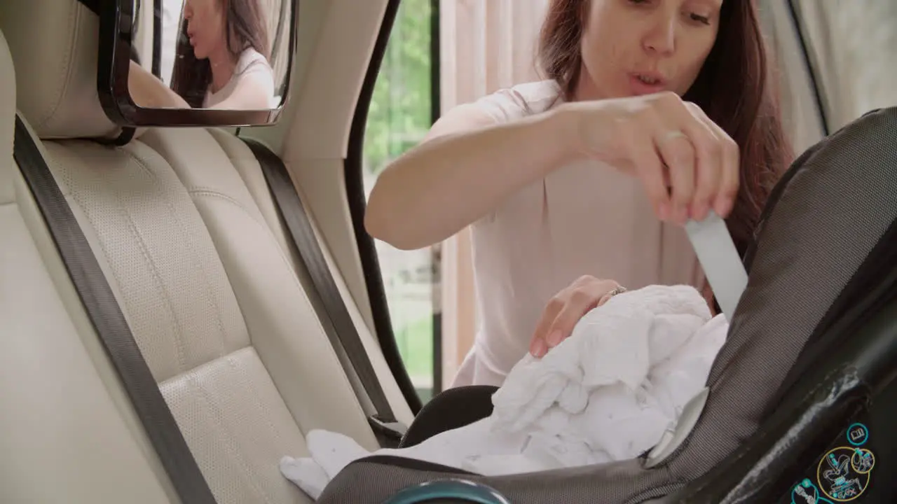 Mother Putting Baby Son Into Car Travel Seat