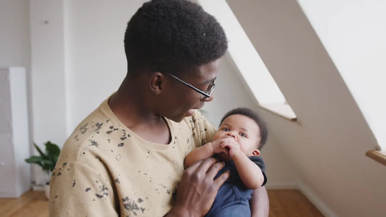 Close Up Of Loving Father Holding Newborn Baby Son At Home In Loft Apartment