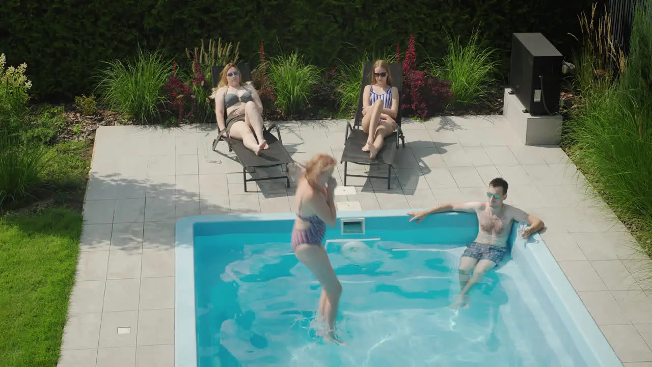 A cheerful family is relaxing by the pool a woman jumps into the water Enjoying a warm summer day