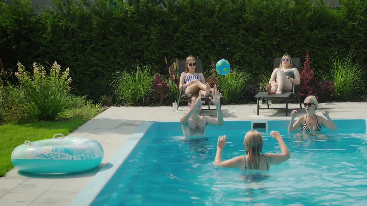 A friendly family is relaxing by the pool playing ball Having a good time together on a hot summer day