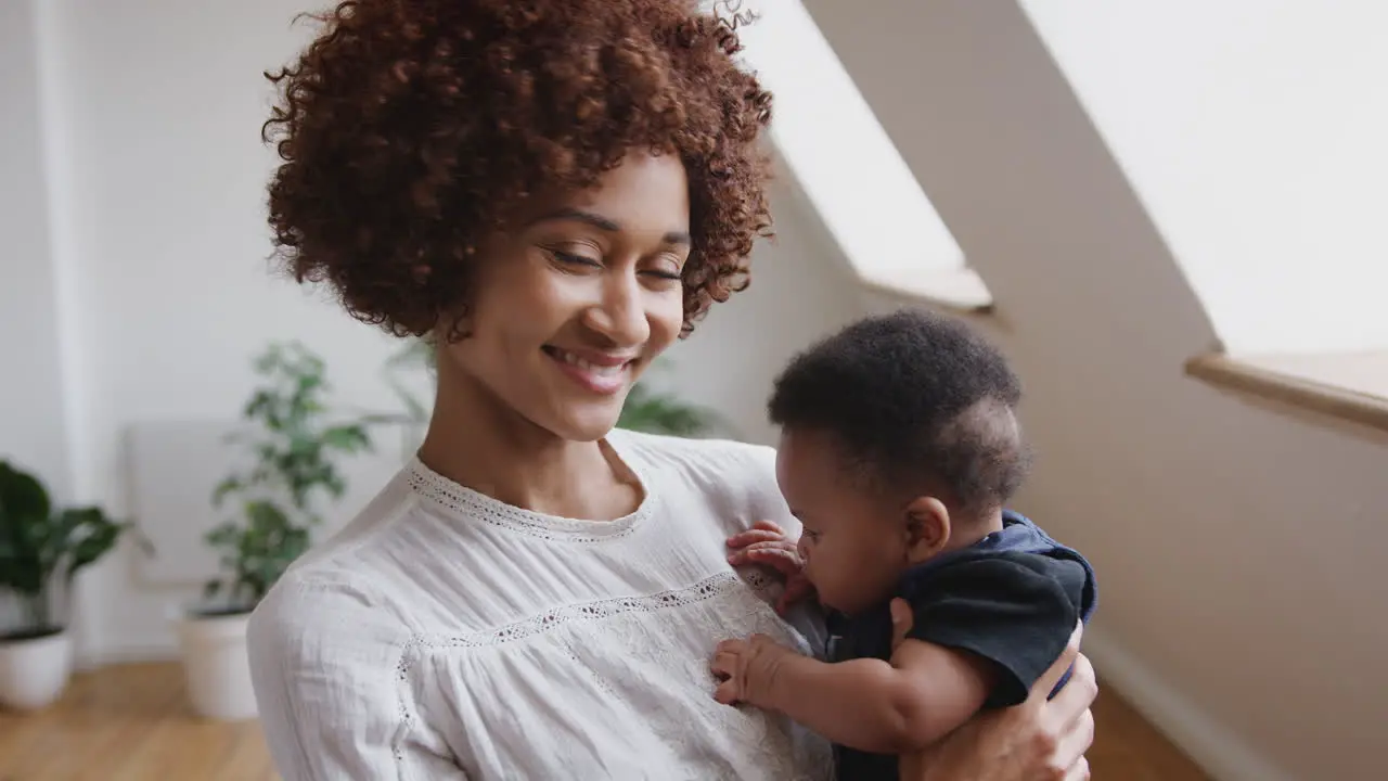 Portrait Of Loving Mother Holding Newborn Baby Son At Home In Loft Apartment