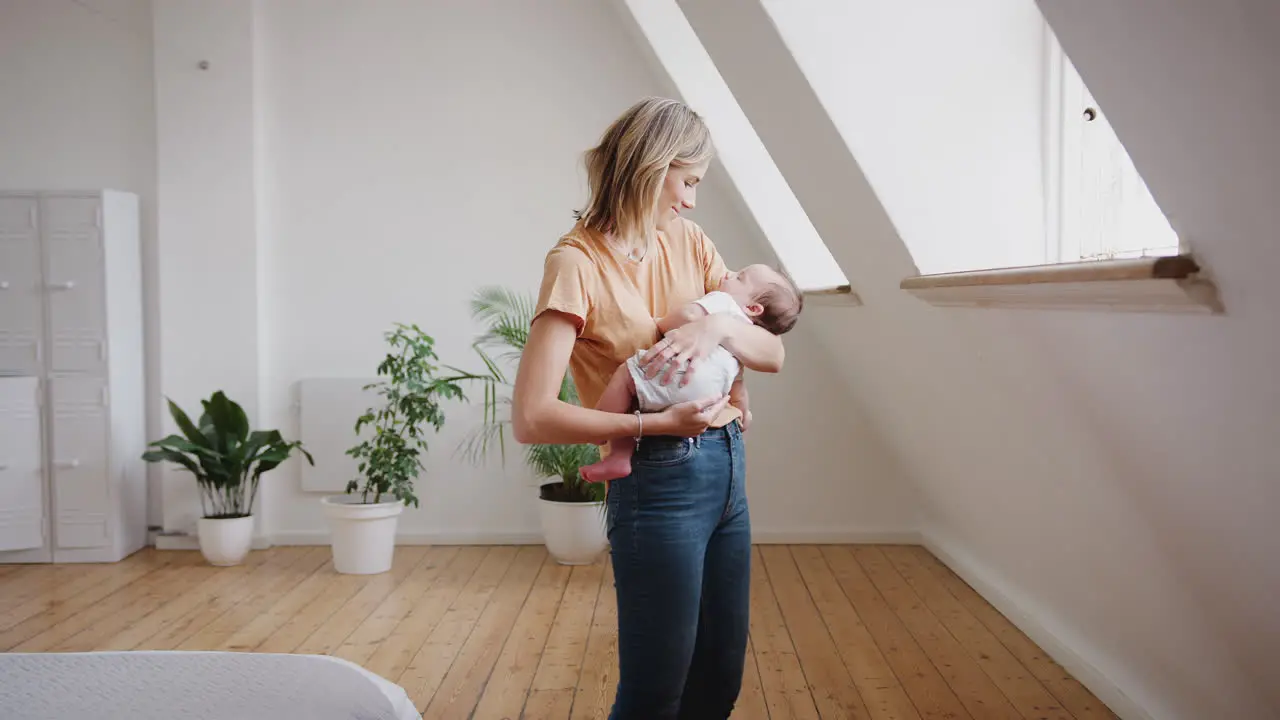 Loving Mother Holding Sleeping Newborn Baby At Home In Loft Apartment