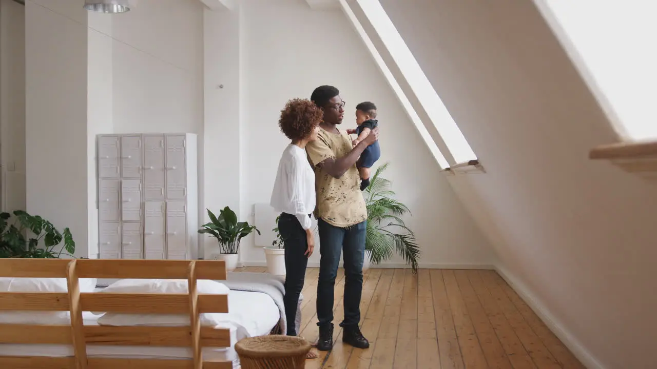 Loving Parents Holding Newborn Baby Son At Home In Loft Apartment