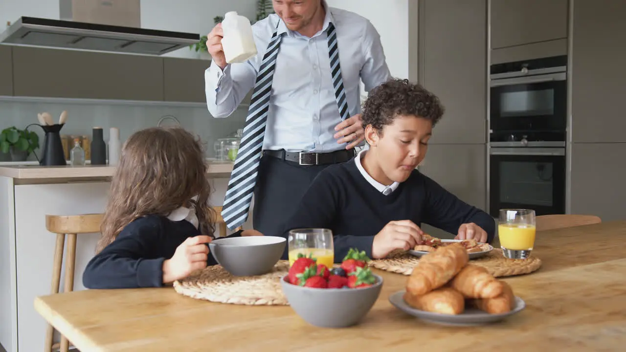 Businessman Father In Kitchen Helping Children With Breakfast Before Going To School