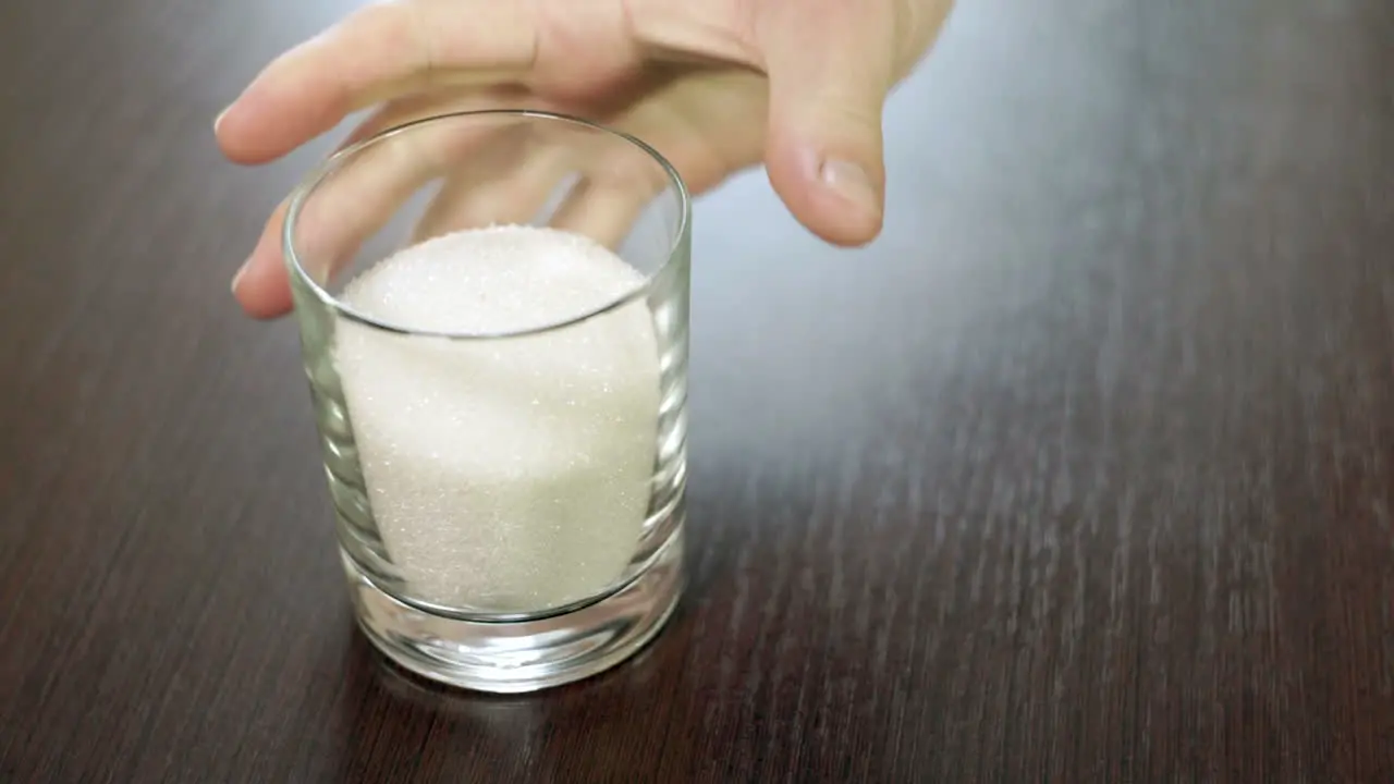 Sugar in glass Baking ingredients Cup full of sugar Hand taking cup of sugar