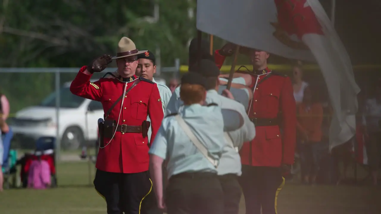 RCMP officer salutes Canadian army cadets holding flags in slow motion