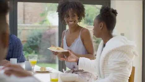 Mother Hands Plate of Croissants to Young Daughter During Breakfast