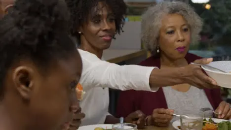 Mother of Family Passing Bowl of Potatoes Across Dining Table 