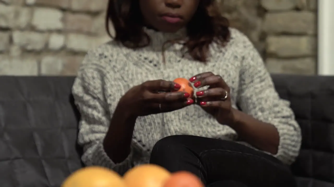 Pull focus to a woman with a mandarin orange sitting on