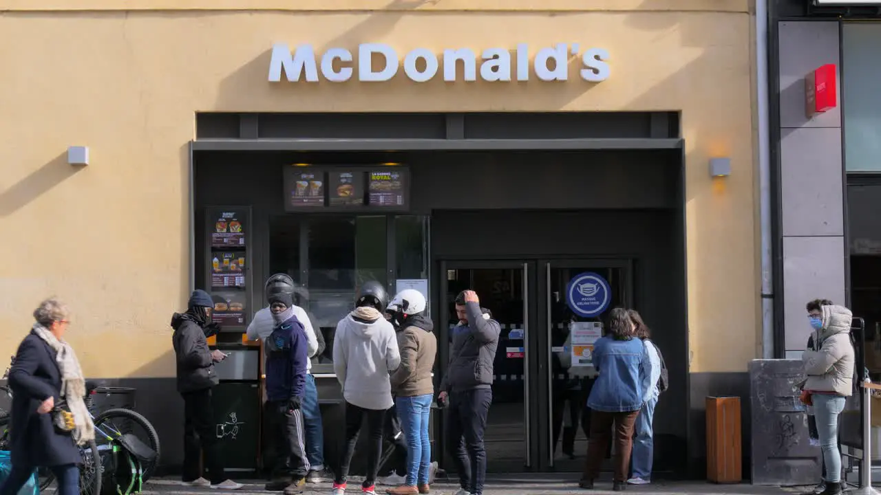 A group of food delivery drivers stand outside of a McDonalds waiting for their orders