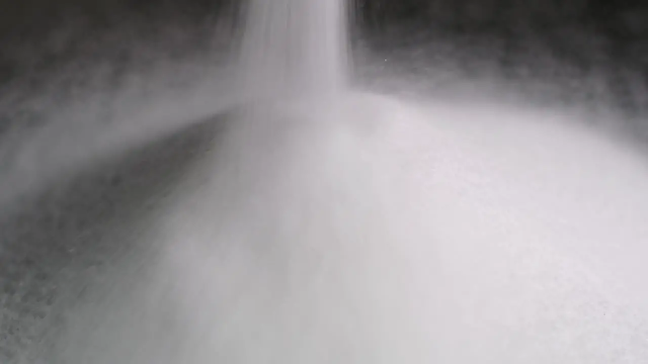 Detail video of white sugar poured on dark background