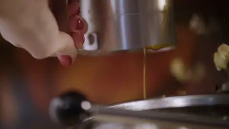 Female hand pouring oil into machine for popcorn production