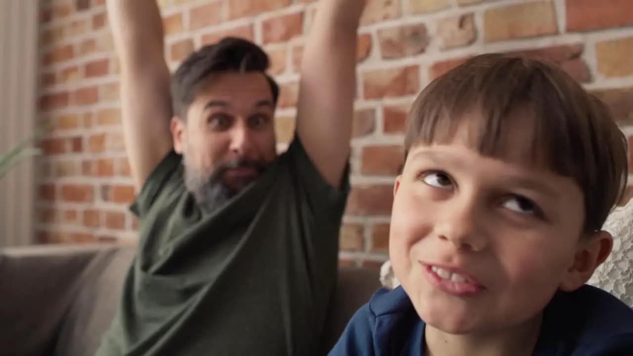 Video of father and son playing video game on couch