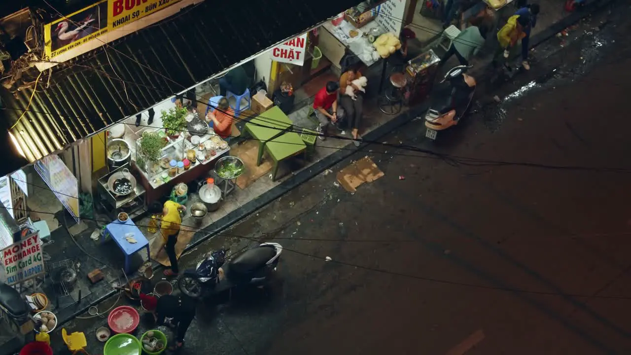 Man making Vietnamese food with vegetables at a Vietnam Street food stall at night in Hanoi looking out from the city balcony