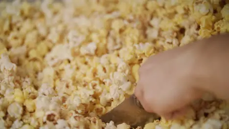 Human hand pouring ready popcorn from popcorn machine by ladle