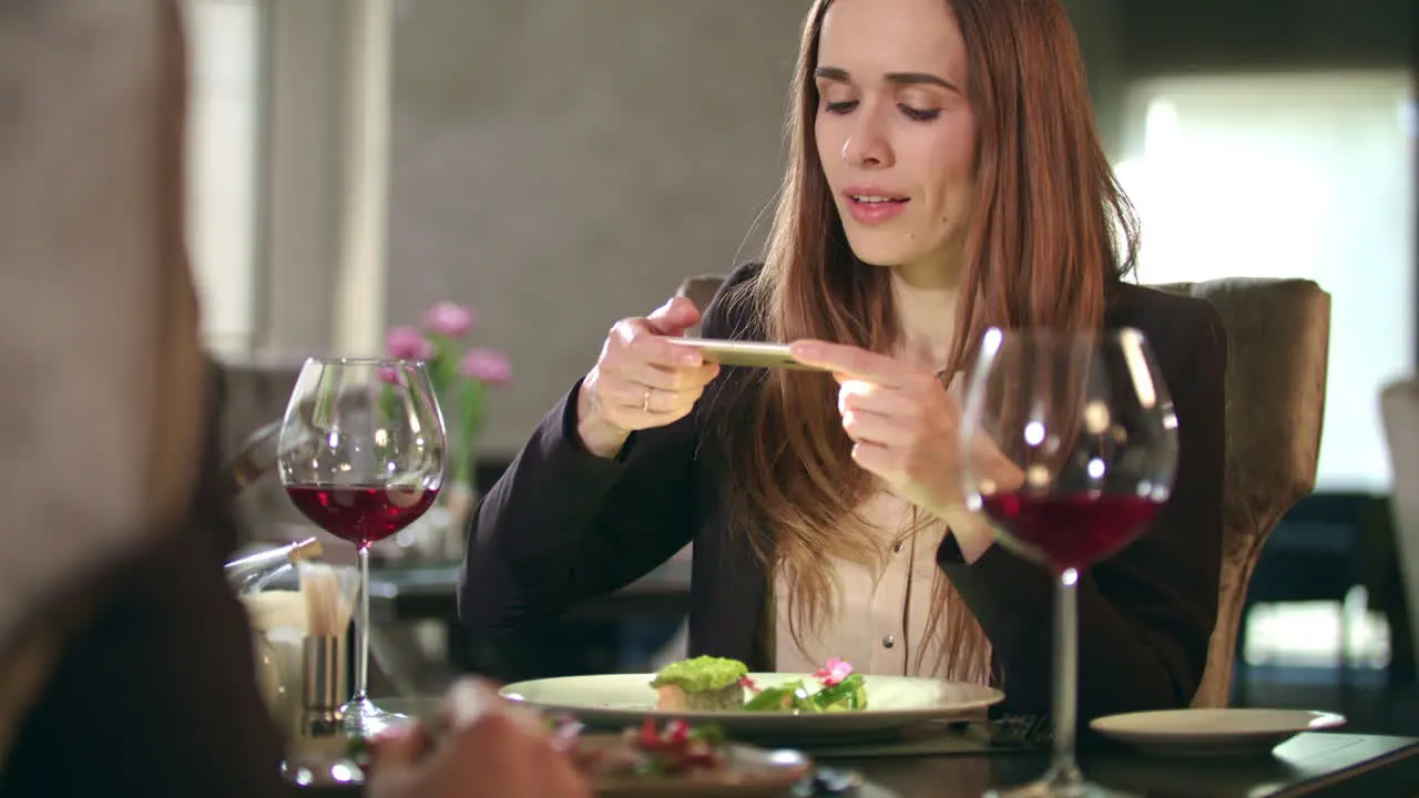 Businesswoman taking food photo on smartphone at restaurant