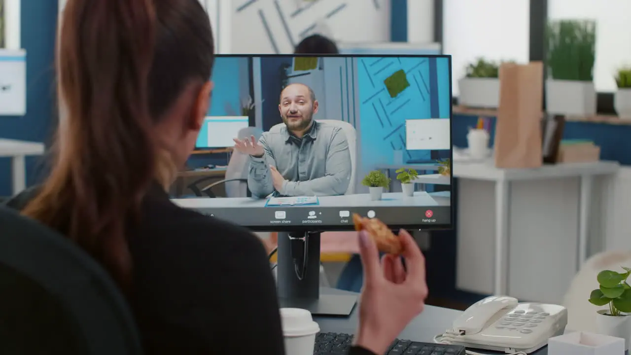 Executive manager eating delivery takeaway pizza during online videocall conference meeting