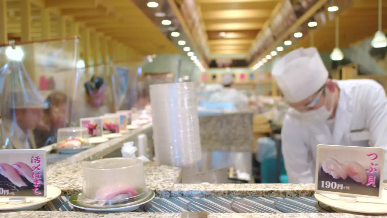 Kaiten-zushi Chefs Wearing Face Shield And Plastic Sheet Barrier Between Customers New Normal Scene In A Conveyor Belt Sushi Restaurant In Tokyo Japan selective focus