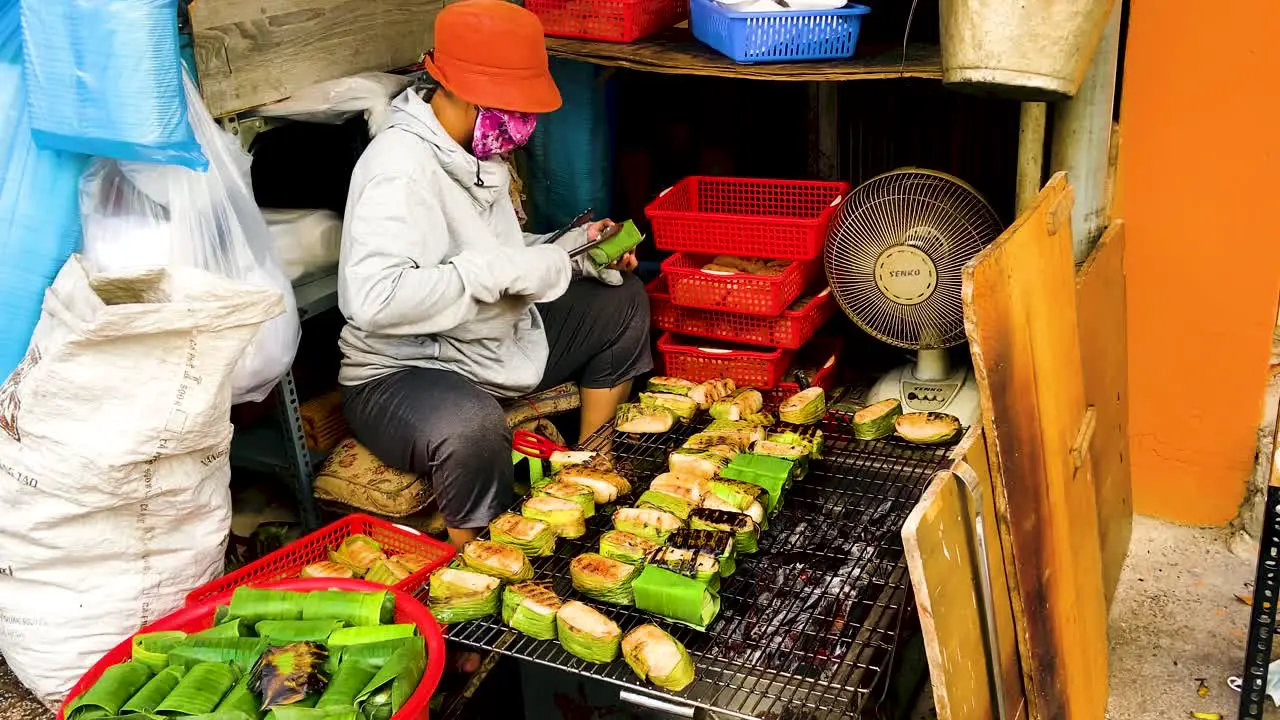 Saigon Woman Grilling Street Food Wrapped In Banana Leaves In Ho Chi Minh Vietnam close up slowmo