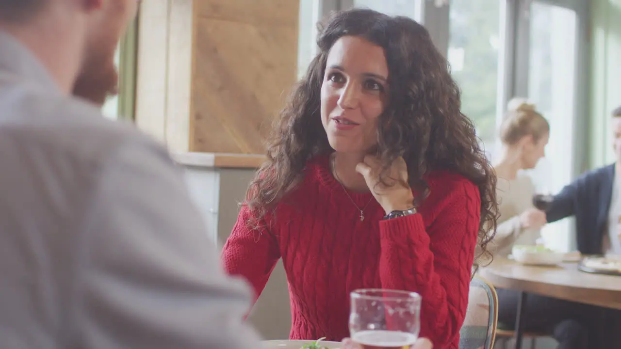 Smiling Young Couple On Date Enjoying Pizza In Restaurant Together