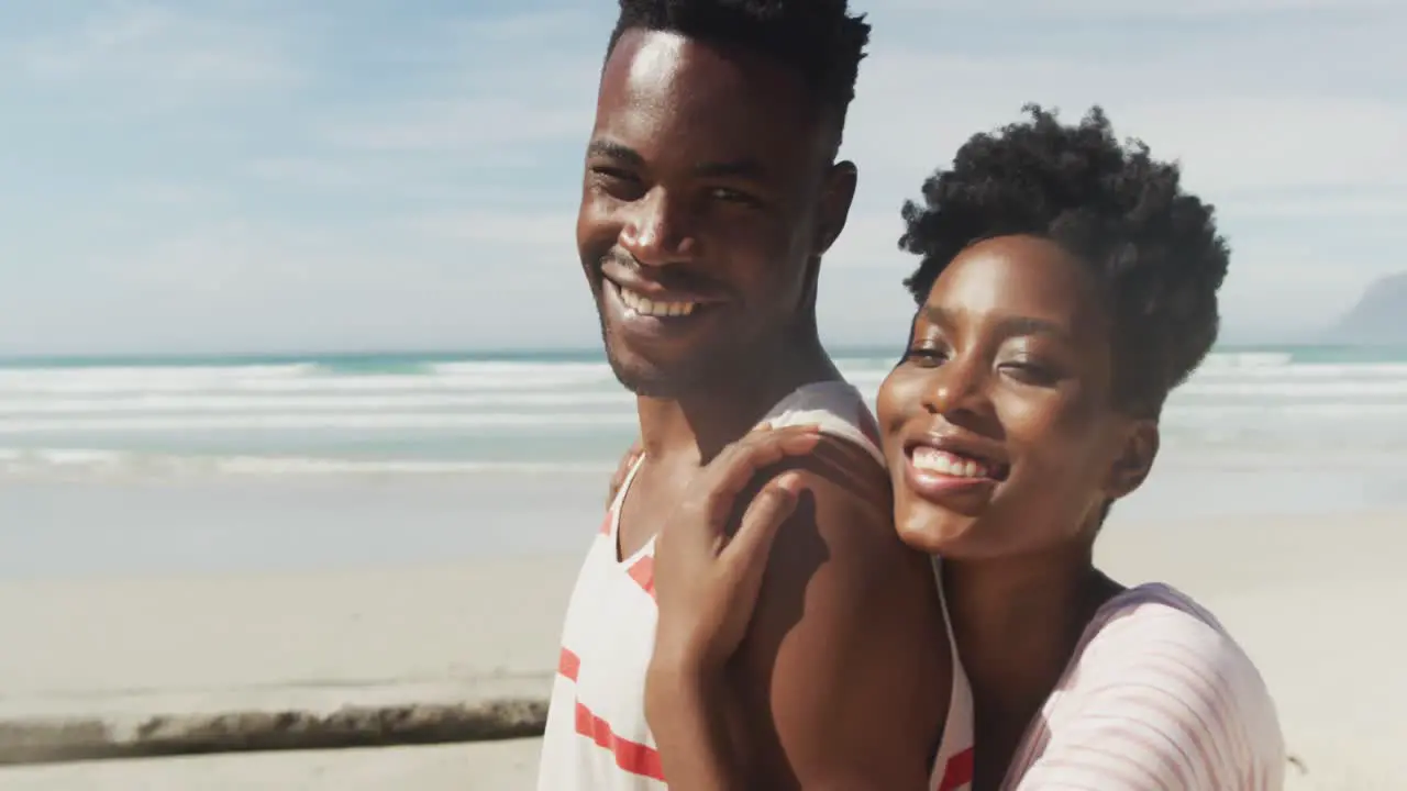 Portrait of happy african american couple embracing on sunny beach