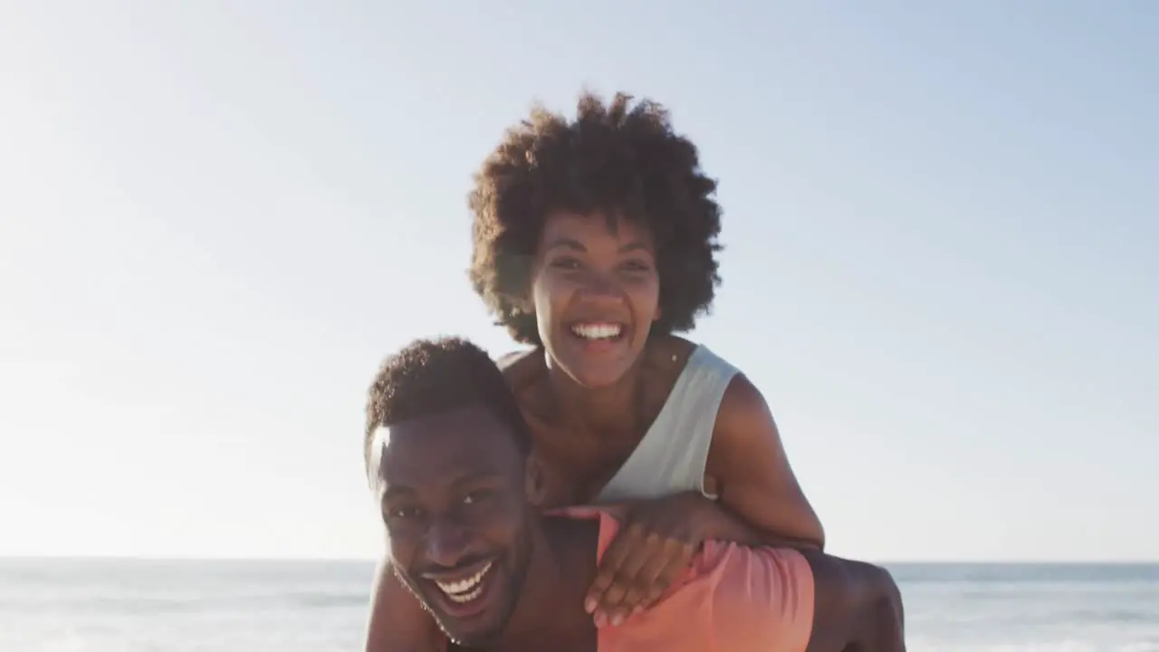 Portrait of smiling african american couple embracing on sunny beach