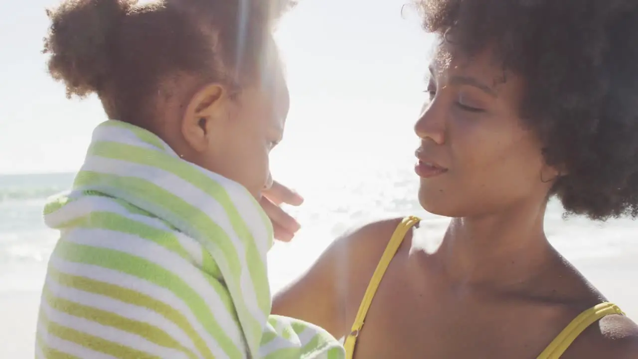 Smiling african american mother toweling off her daughter on sunny beach