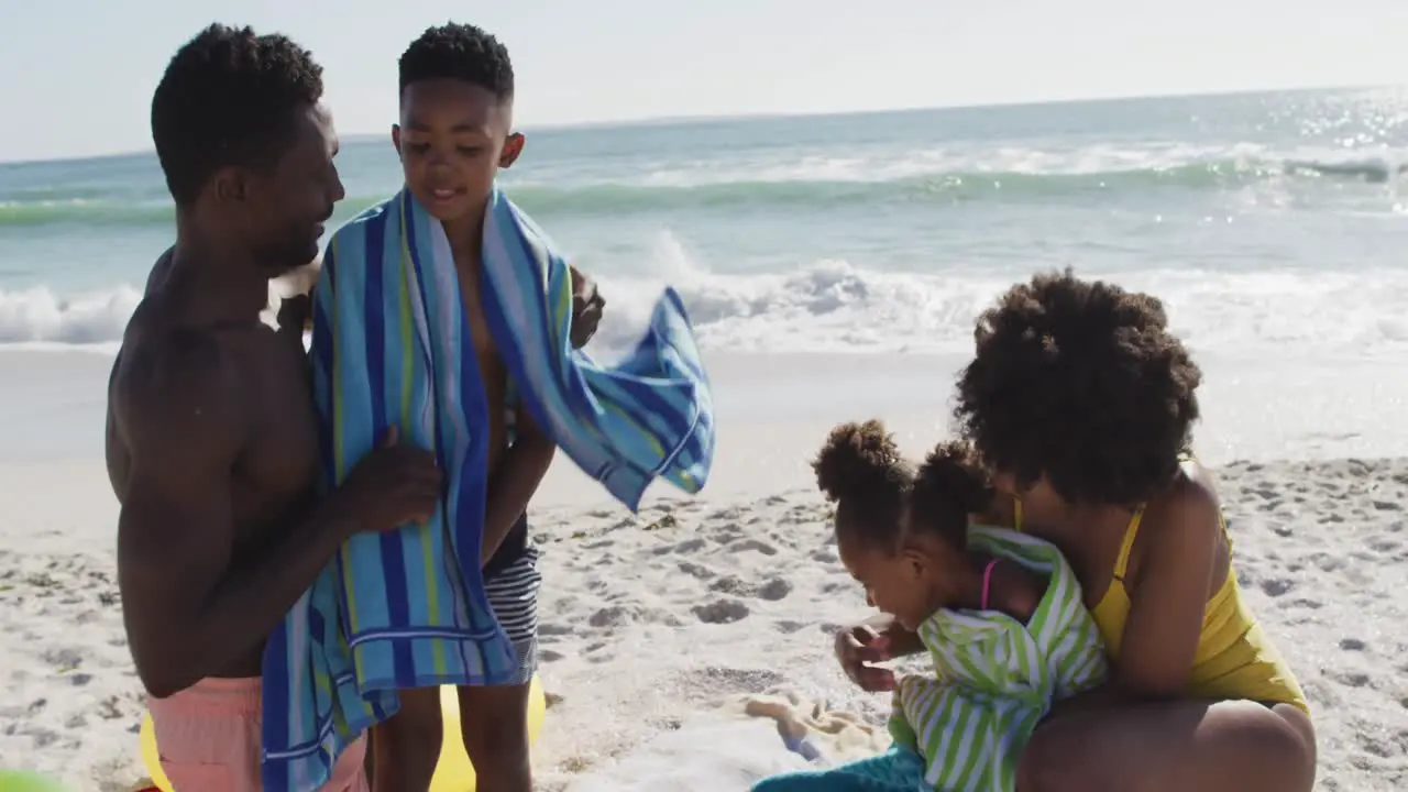 Smiling african american parents toweling off their children on sunny beach