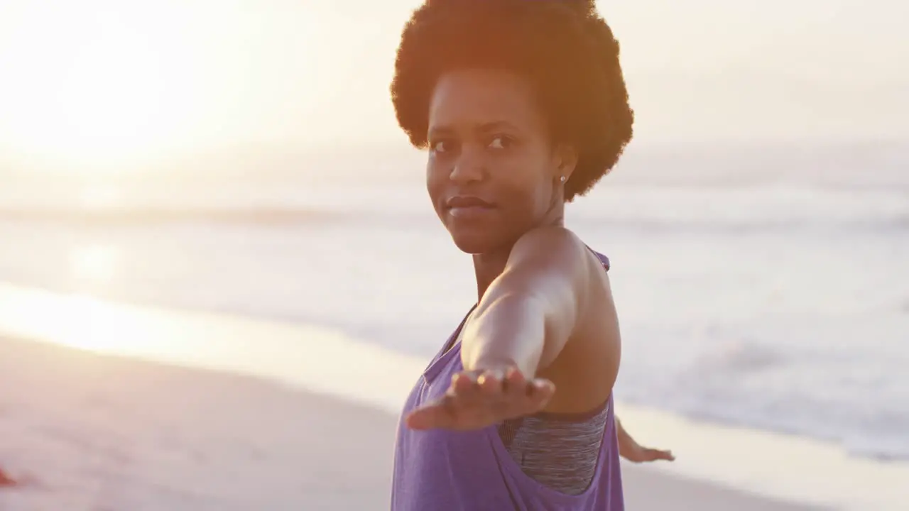 Happy african american woman practicing yoga on sunny beach