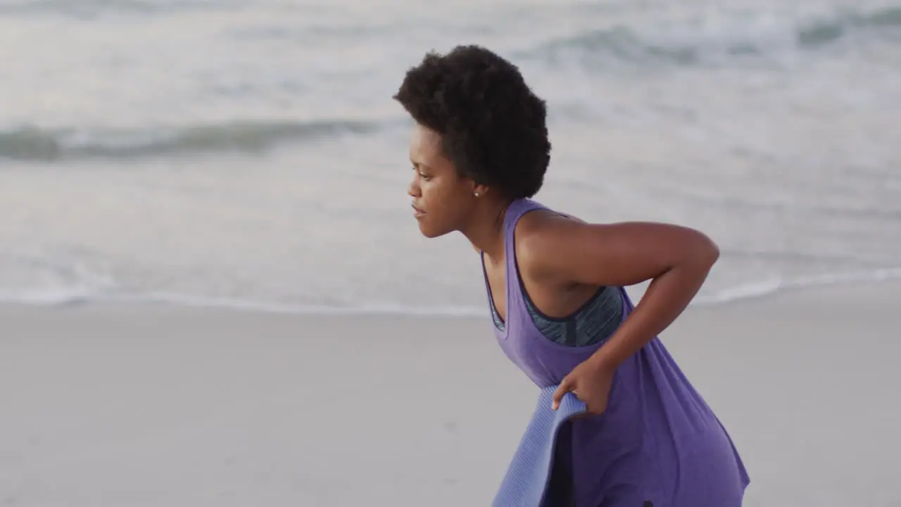 African american woman with yoga mat on sunny beach